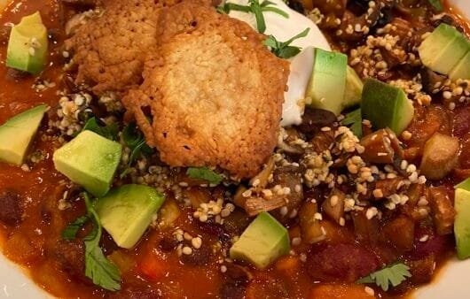 Bol de chili végétalien copieux avec avocat et quinoa croustillant