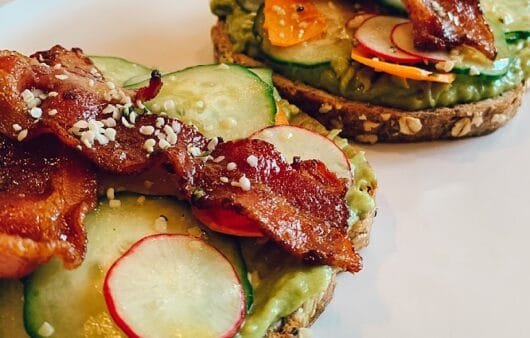 Tostada crujiente de aguacate, tocino, verduras encurtidas y semillas de cáñamo